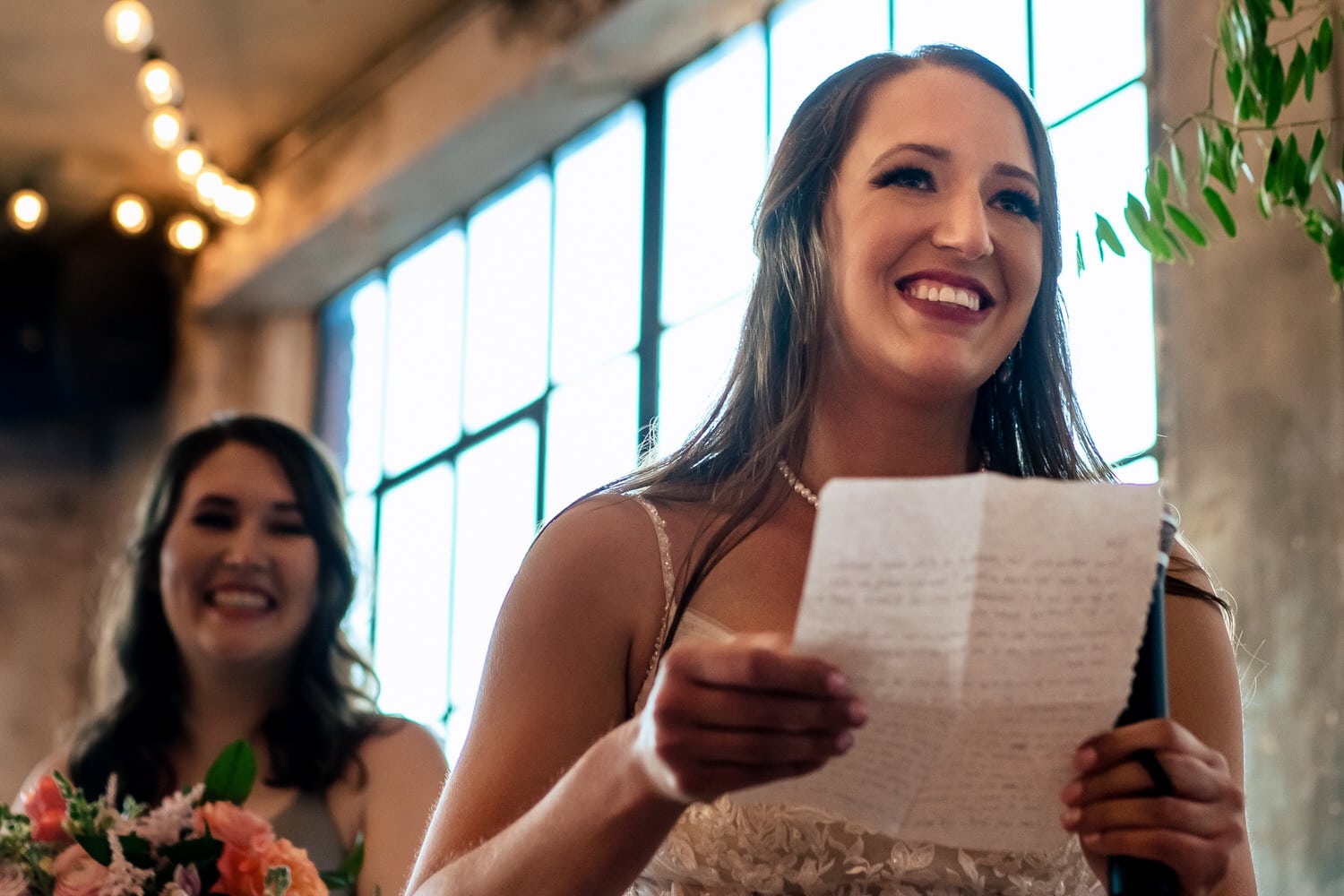 A colorful, candid picture of a bride smiling at her groom as she reads her wedding vows to him during their wedding ceremony at The Bauer in Kansas City. 
