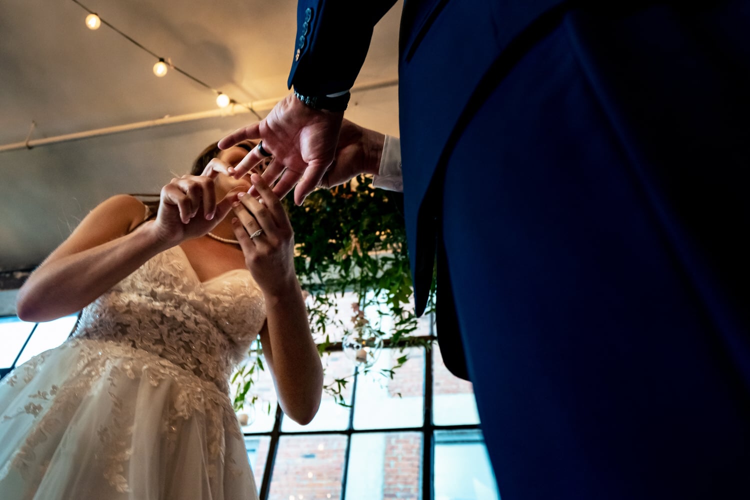 A tight picture taken from the ground looking up of a bride putting a wedding band on her groom's hand during their wedding ceremony at The Bauer in Kansas City. 