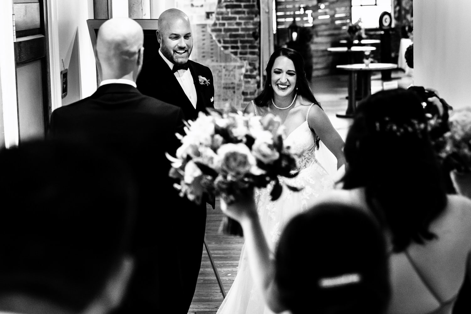 A candid black and white picture of a bride and groom excitedly smiling and embracing their wedding party moments after their wedding ceremony in Kansas City. 