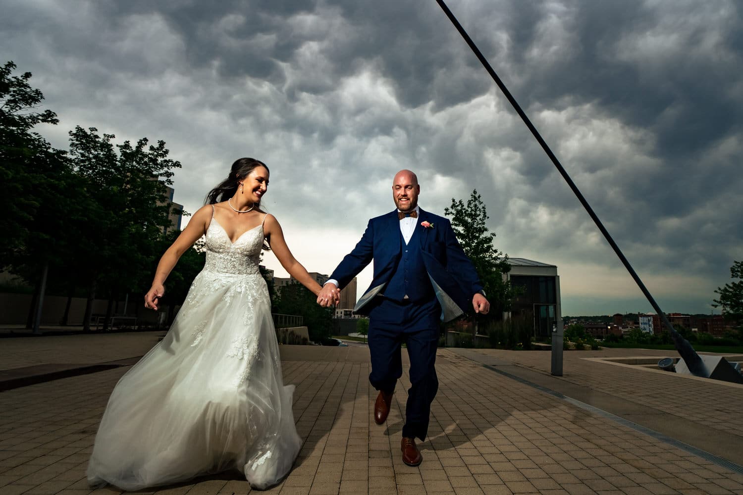 A colorful, candid picture of a bride and groom sprinting towards the camera at the Kauffman Center for the Performing Arts in Kansas City. 