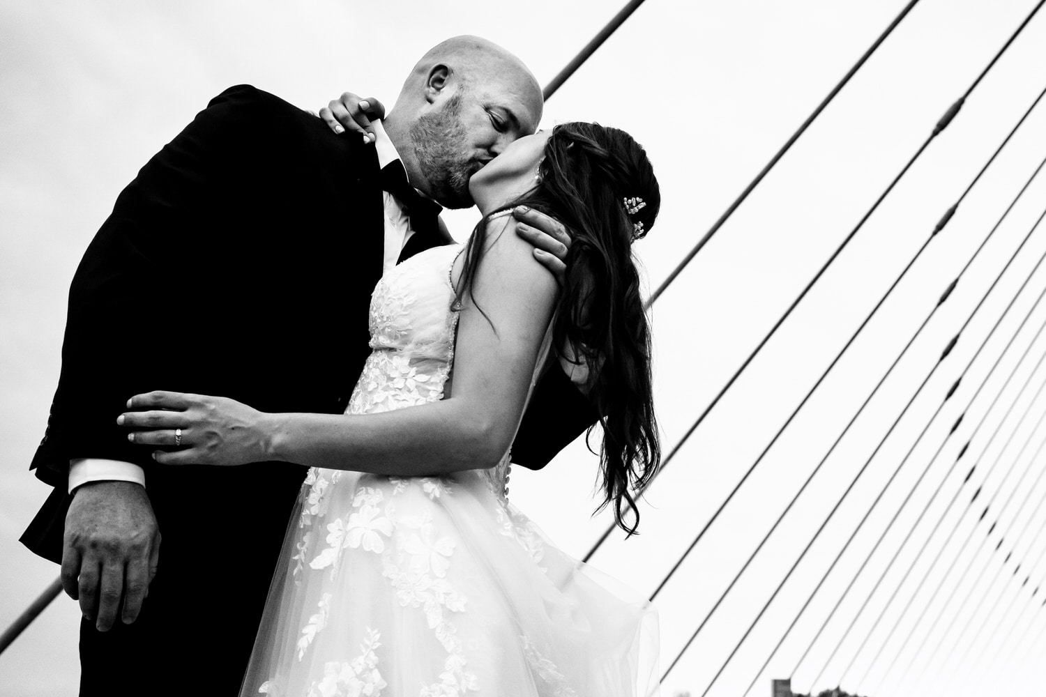 A candid black and white picture of a bride and groom leaning in to share a kiss on their wedding day in Kansas City. 