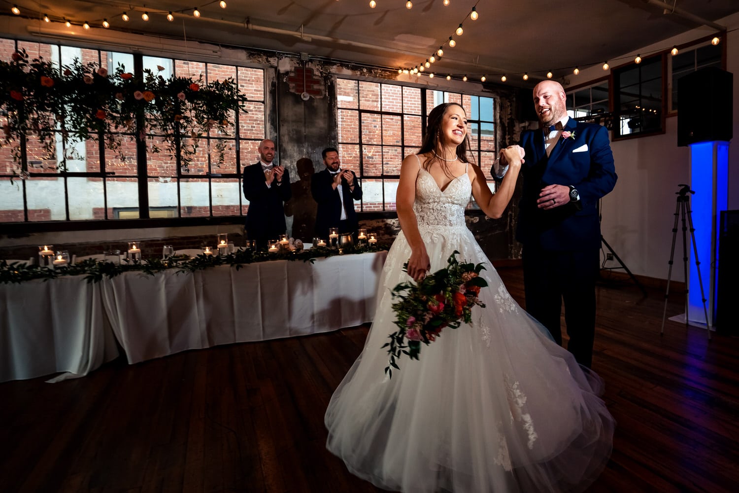 A colorful, candid picture of a groom twirling his bride as they enter their wedding reception at The Bride and The Bauer in Kansas City. 