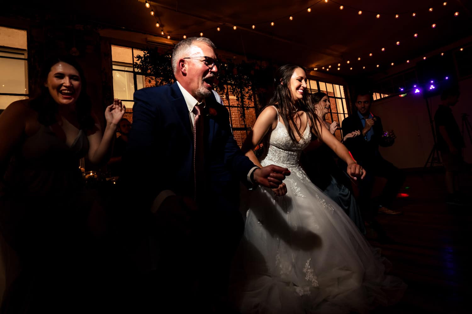 A colorful, candid picture of a bride dancing with her dad during a summer wedding reception at The Bride and the Bauer in Kansas City. 