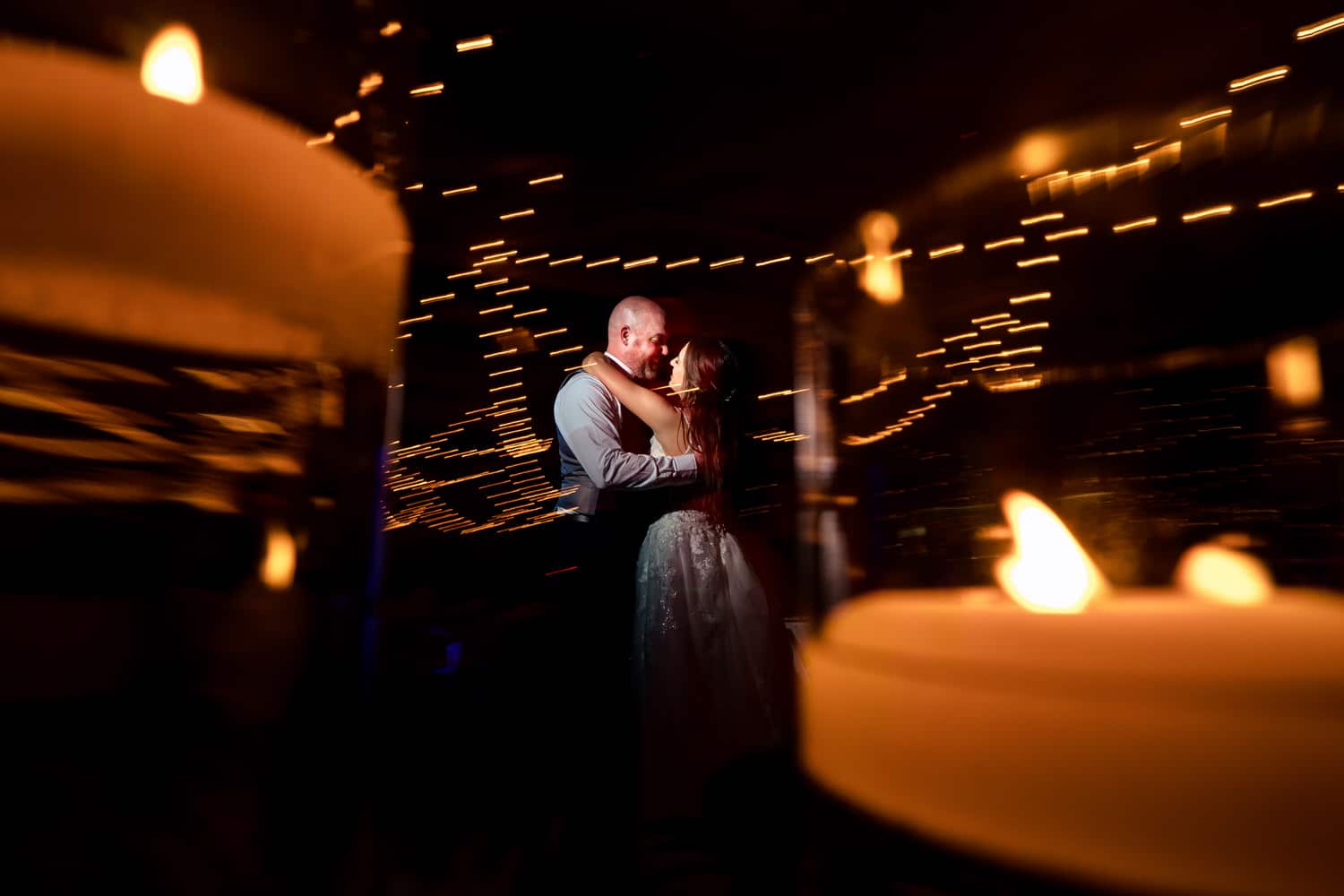 A candid picture taken between two floating candles of a bride and groom sharing a dance during their wedding reception at The Bride and The Bauer in Kansas City. 