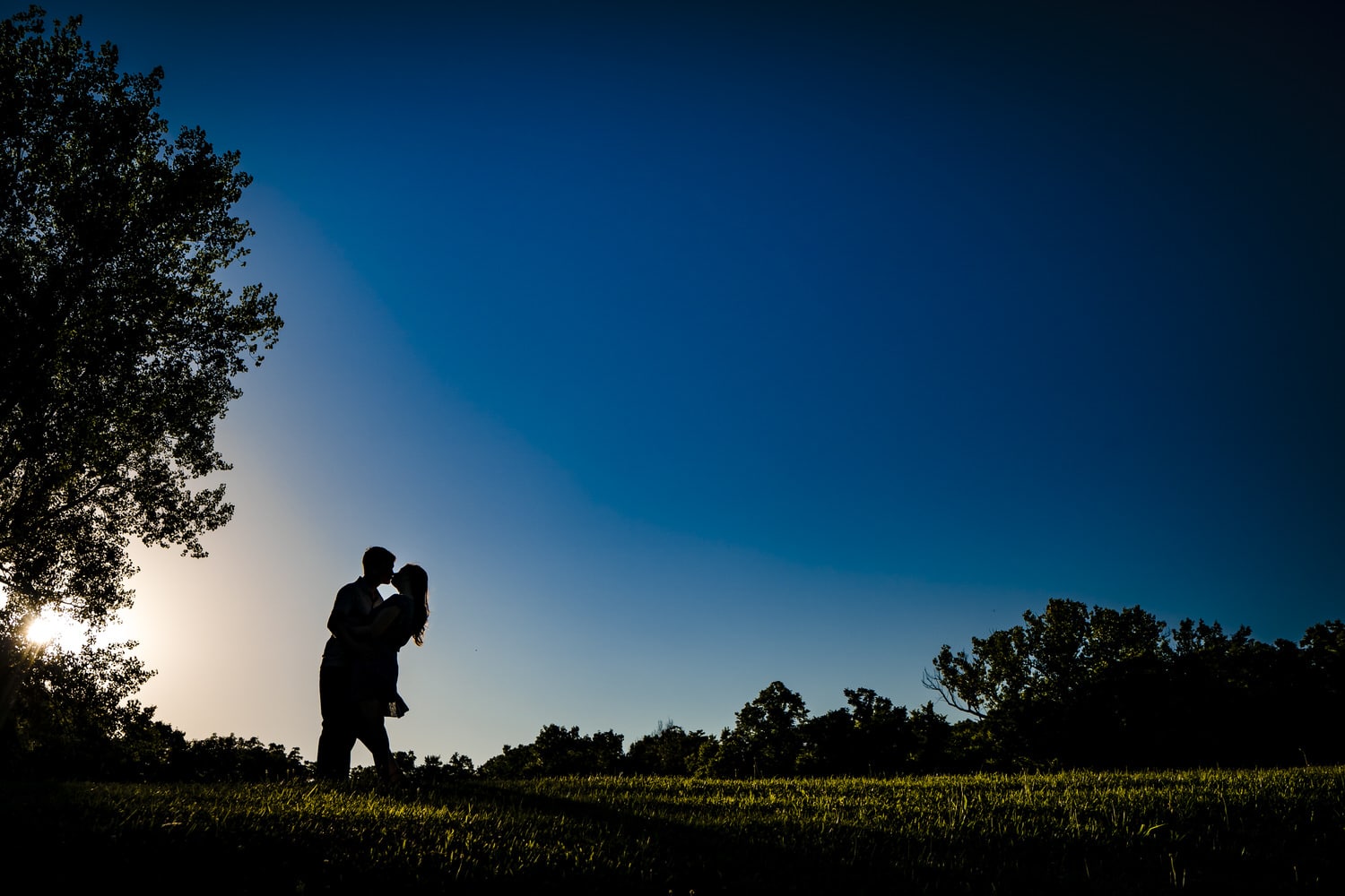 A colorful, candid silhouette of an engaged couple sharing an embrace during a summer engagement session in Kansas City. 
