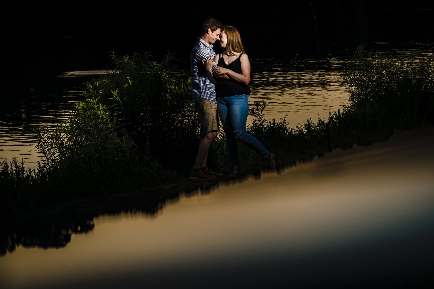 A colorful portrait of an engaged couple sharing an embrace during their summer engagement session at Wyandotte County Park. 