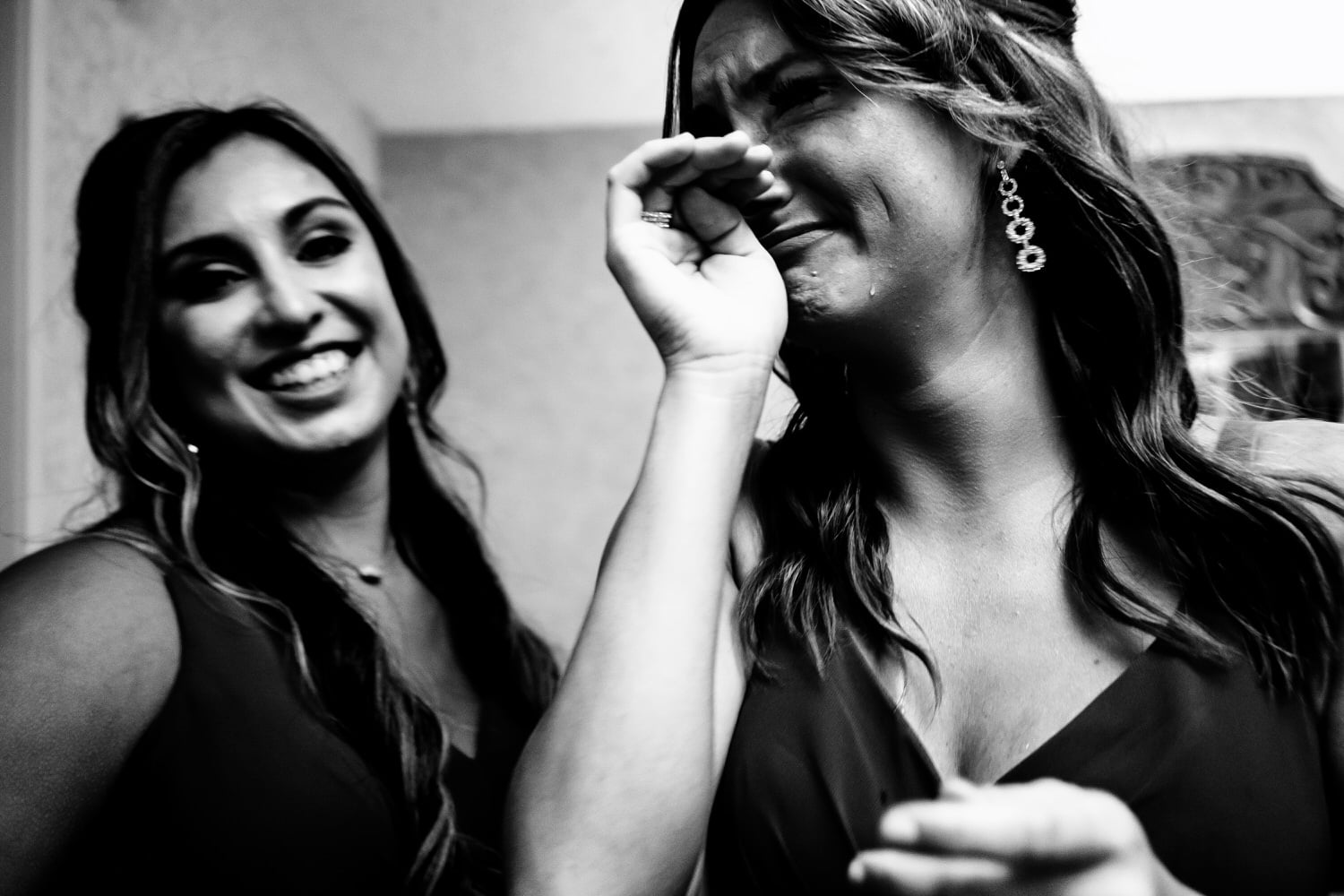 A candid black and white picture of a bridesmaid with tears rolling down her face as she sees the bride for the first time on a summer wedding day. 
