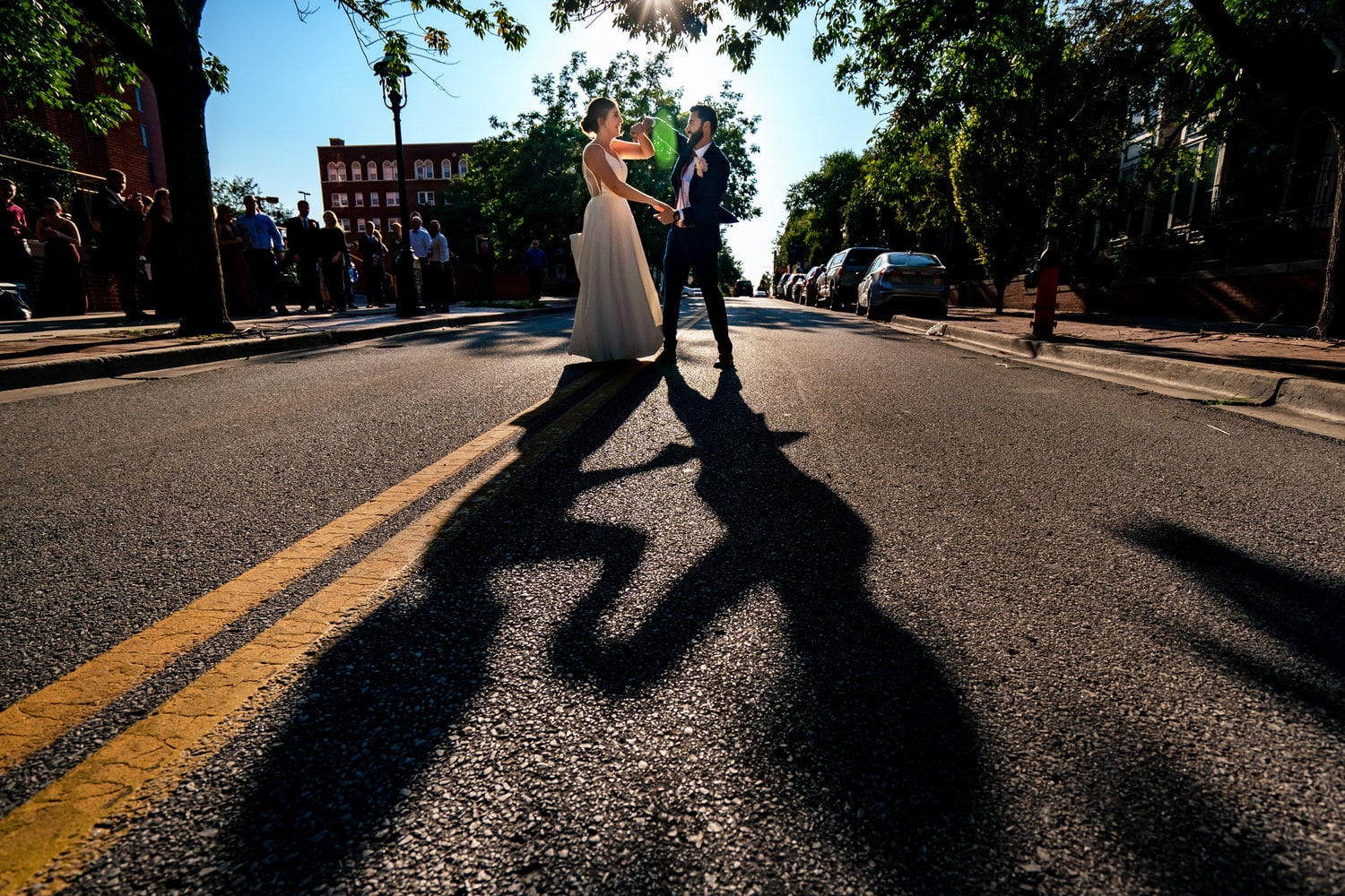 A colorful, candid picture of a bride and groom dancing in the middle of a downtown Kansas City street on a summer wedding day. 