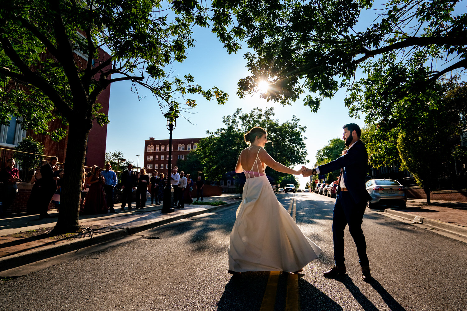 A colorful, candid picture of a bride and groom dancing in the middle of a downtown Kansas City street on a summer wedding day. 