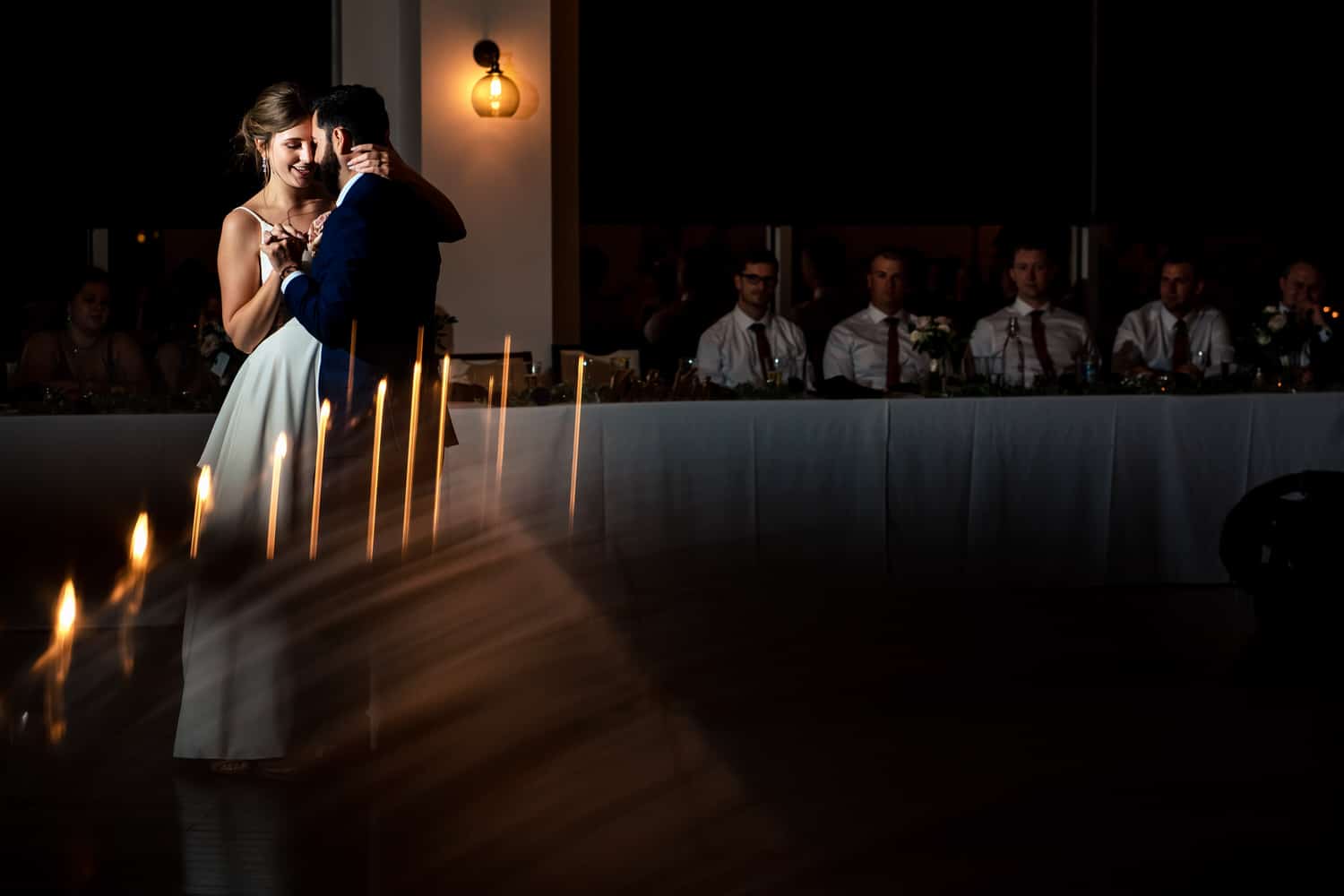 A wide, colorful picture of a bride and groom sharing their first dance during a classic Kansas City wedding reception at Grand Street Cafe. 