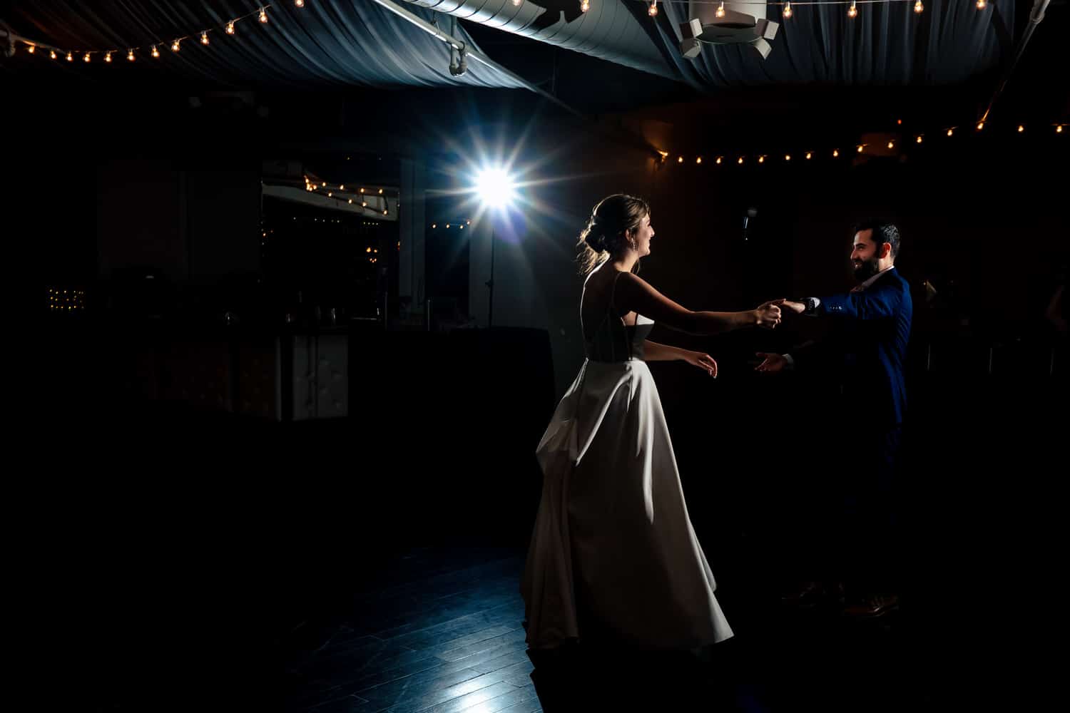 A wide, colorful picture of a bride and groom sharing their first dance during a classic Kansas City wedding reception at Grand Street Cafe. 