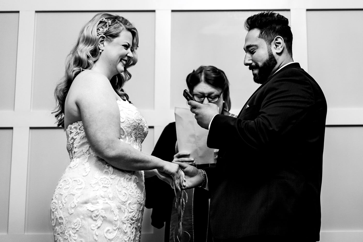 A candid black and white picture of a groom reading his vows to his bride as she smiles at him during their intimate wedding ceremony in Kansas City. 