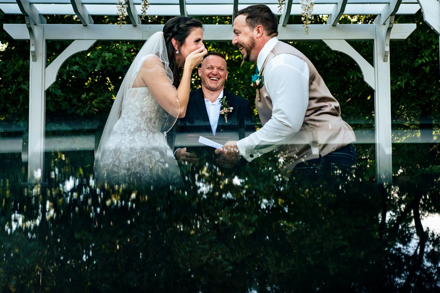 A colorful, candid picture of a bride and groom laughing hysterically during their summer wedding ceremony at Countryside Chalet in Kansas City. 