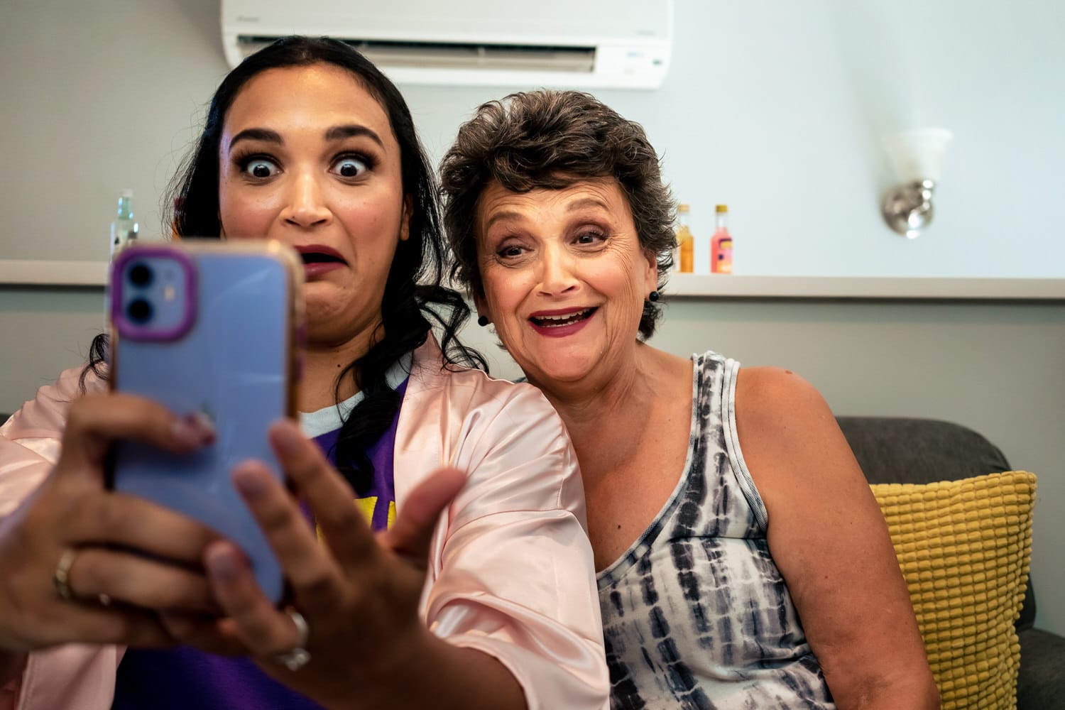 A colorful, candid picture of a maid of honor and mother of the bride making a silly face as they take a selfie. 