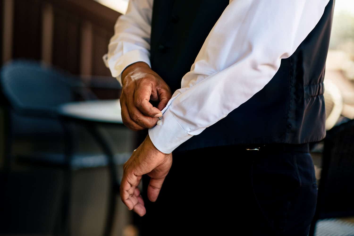 A candid, close-up picture of a man buttoning his shirt sleeves on his summer wedding day at 28 Event Space. 