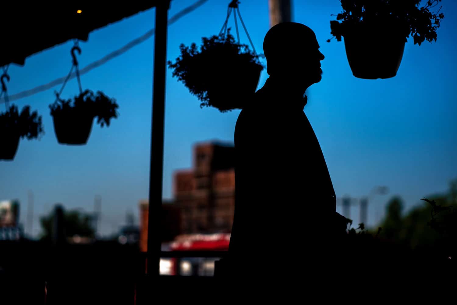 A colorful silhouette of a man standing on a patio, looking off into the distance on his summer wedding day. 
