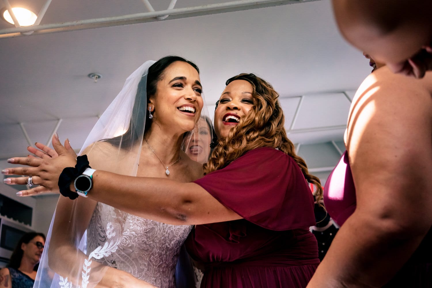 A candid picture of a bridesmaid hugging a bride moments after seeing her for the first time on her summer wedding day. 