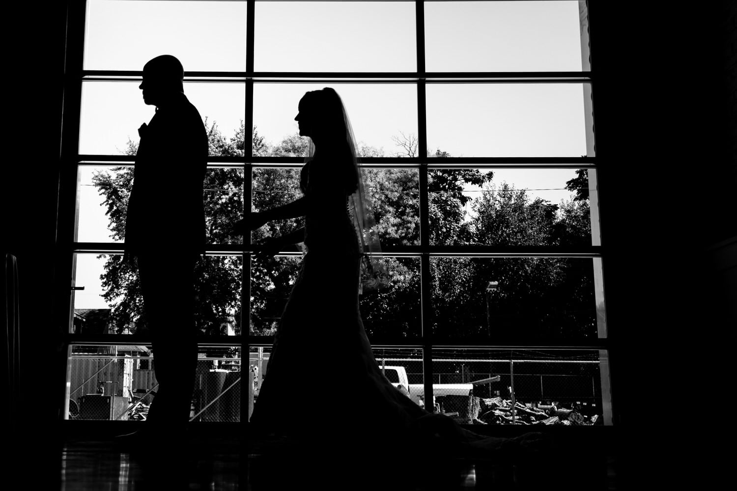 A candid black and white picture of a bride walking up behind her groom on their summer wedding day at The Station in Kansas City. 