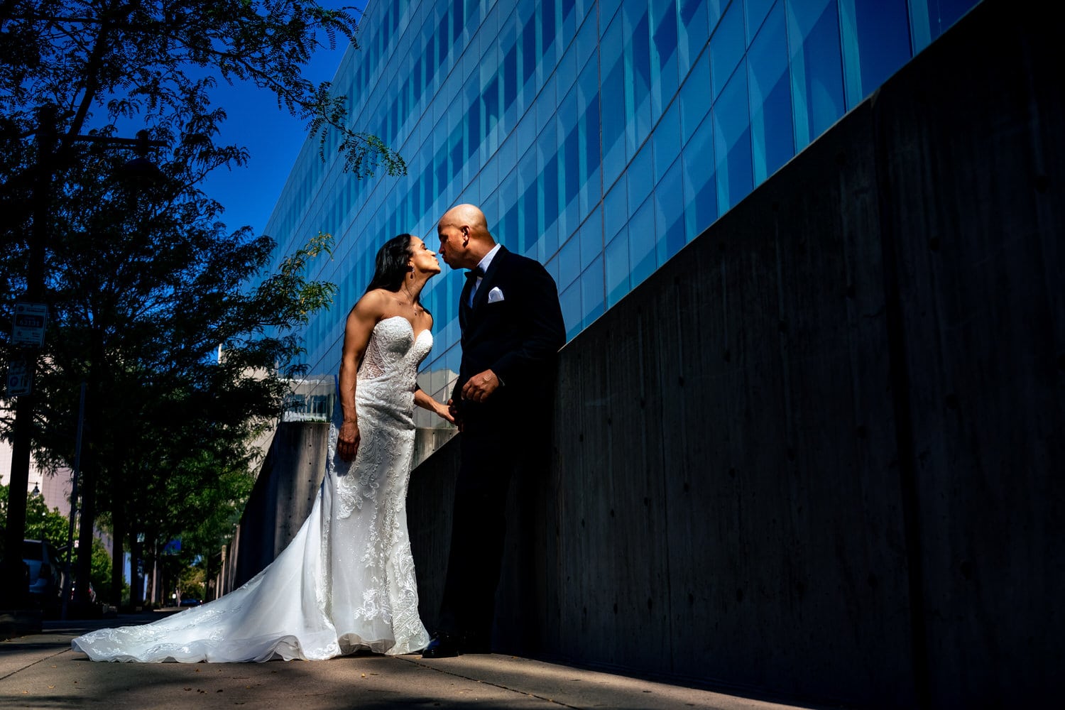 A colorful, candid picture of a bride and groom leaning in to share a kiss on their summer wedding day in Kansas City. 