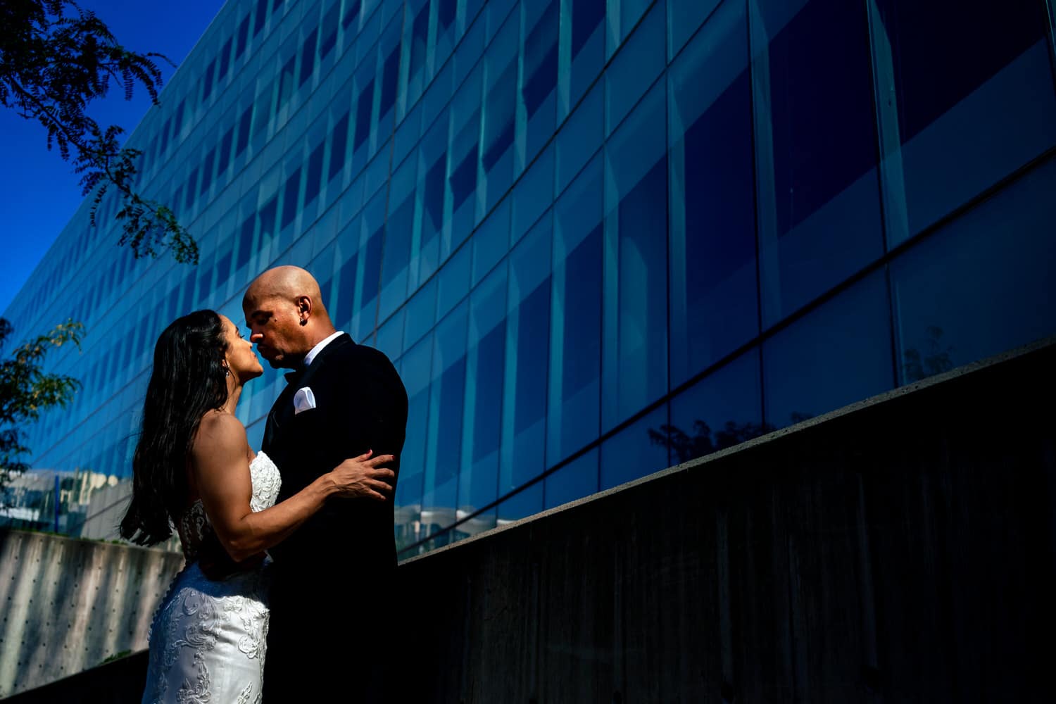 A colorful, candid picture of a bride and groom leaning in to share a kiss on their summer wedding day in Kansas City. 