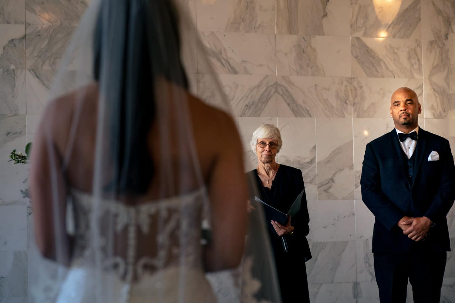 A picture of a groom staring at his bride as she walks down the aisle toward him during their summer wedding ceremony at The Station in Kansas City. 