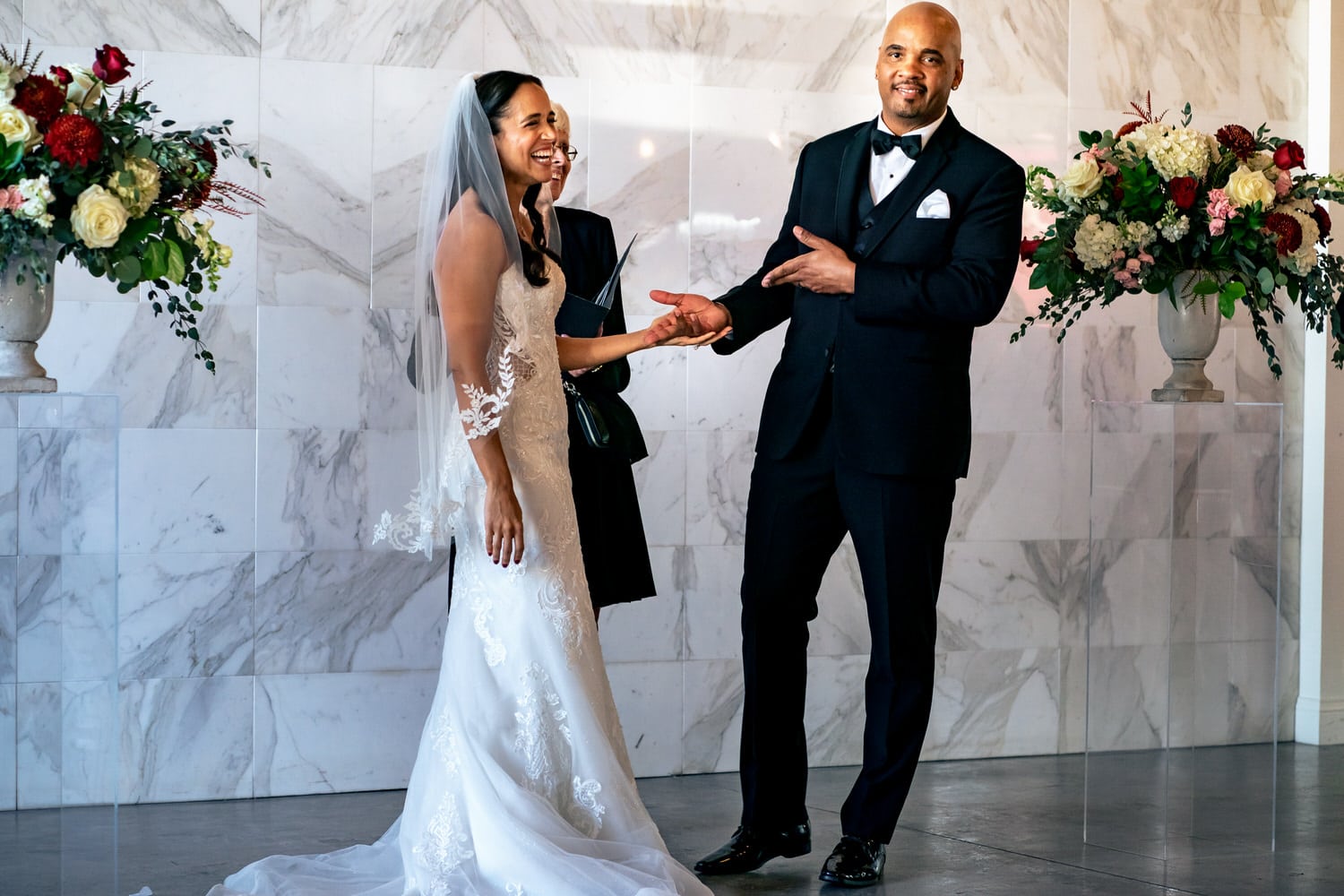 A colorful, candid picture of a groom smiling and pointing happily at his bride at the end of their summer wedding ceremony at The Station in Kansas City. 