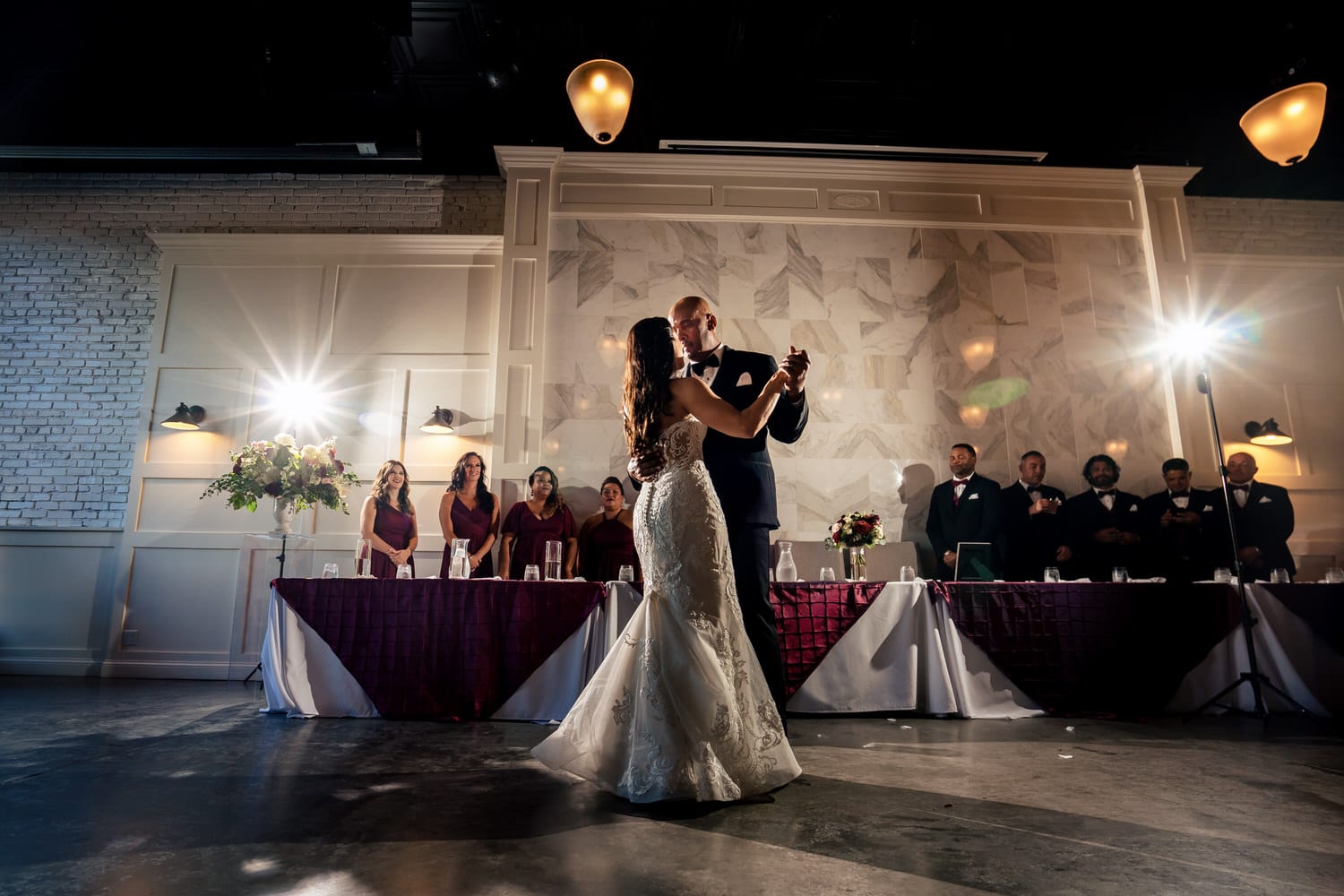 A wide, colorful picture of a bride and groom sharing a dance during their summer wedding reception at The Station at 28 Event Space in Kansas City. 