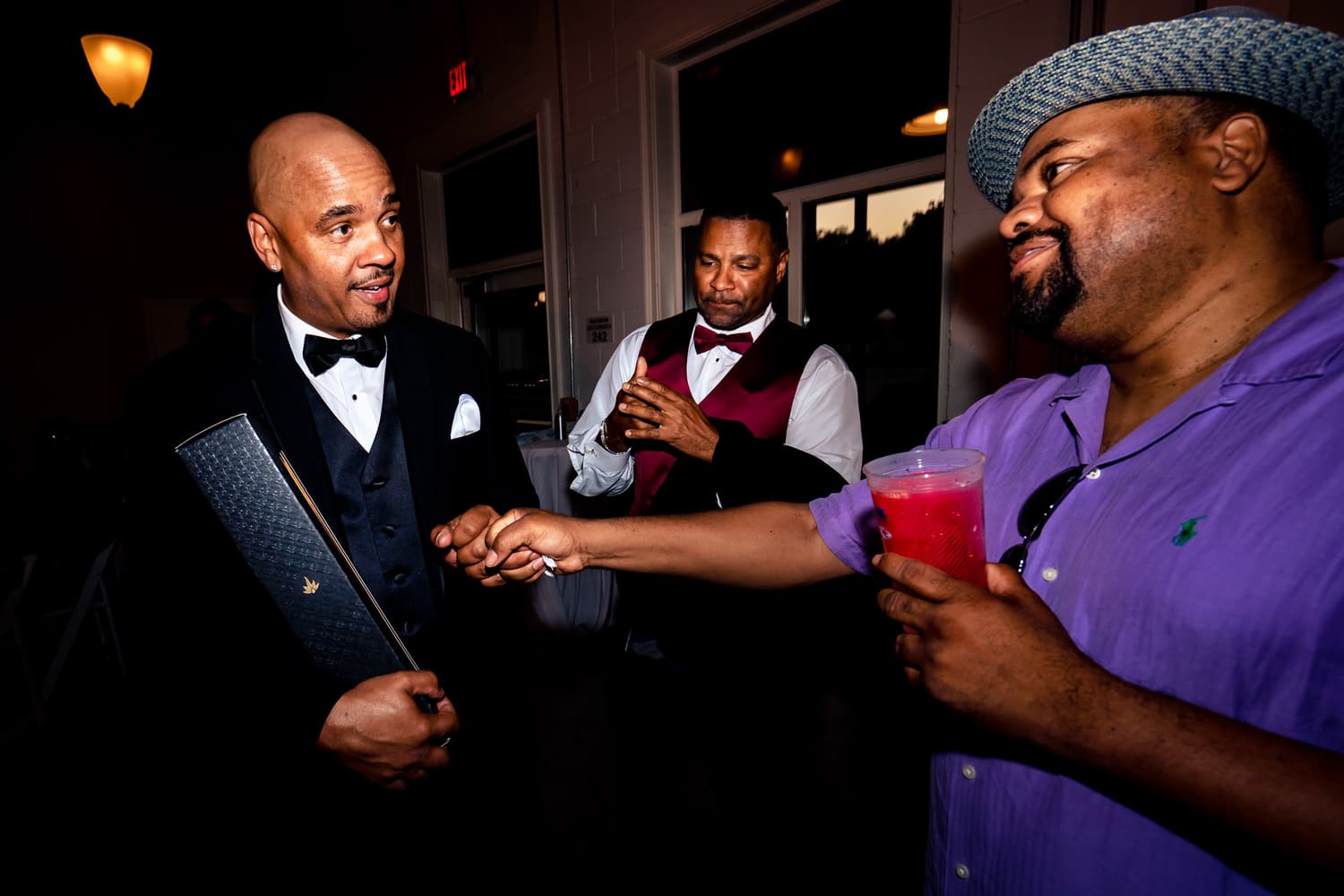 A colorful, candid picture of a groom receiving a wedding gift from a wedding guest. 