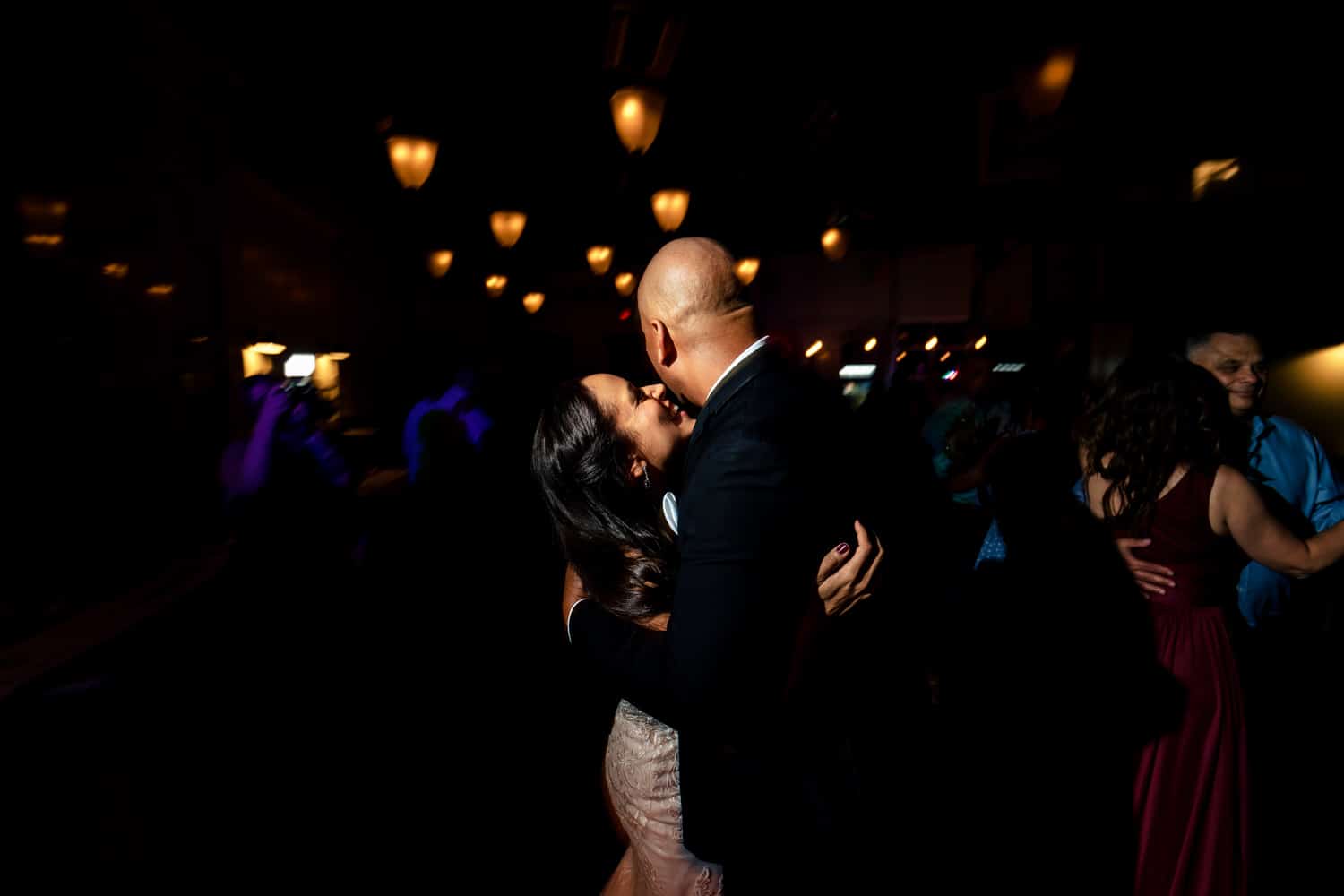 A candid, colorful picture of wedding guests dancing on the dancefloor during a wedding reception at The Station at 28 Event Space in Kansas City. 
