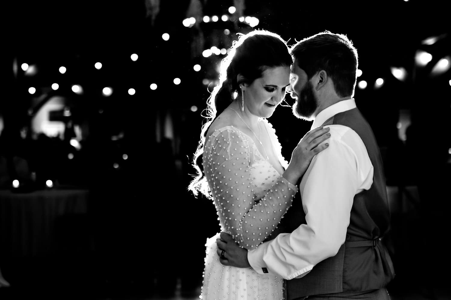A candid black and white picture of a bride and groom sharing their first dance during their fall wedding reception at Timber Creek Event Space. 
