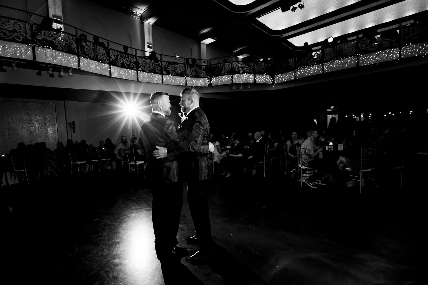 A candid picture of two grooms sharing their first dance at The Madrid Theatre on their fall wedding day in Kansas City. 